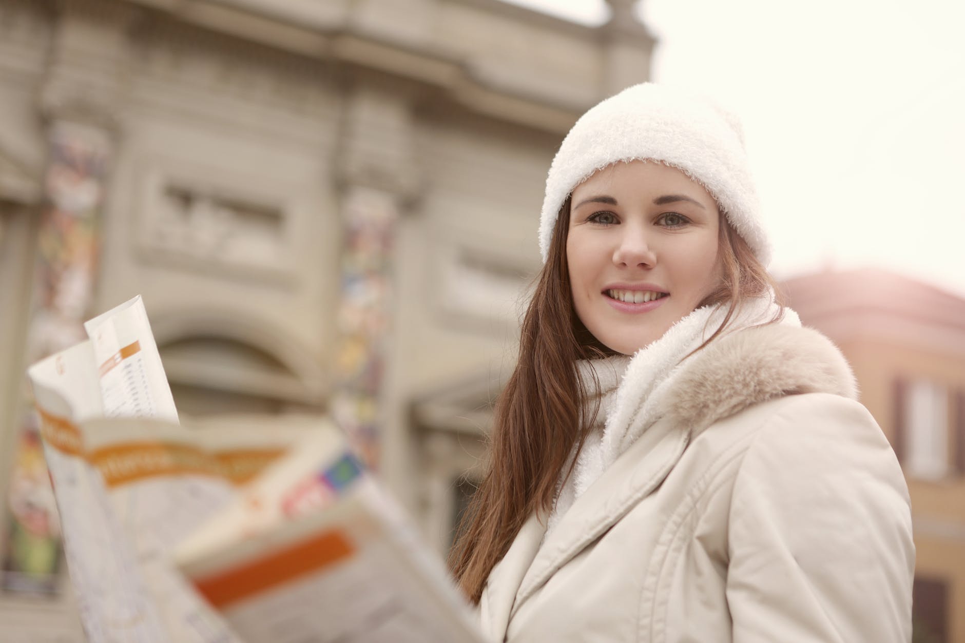 young woman in white fur coat holding a road map